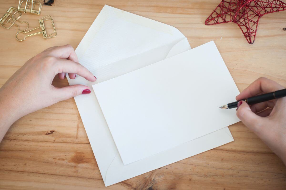 The image shows a girl's hand and writing on the paper to put inside an envelope which means to write personalized thank-you notes for family or friends in a meaningful way to make them feel seen and loved.