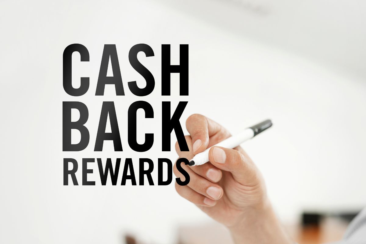 A man's hand is writing a cash back rewards wording.