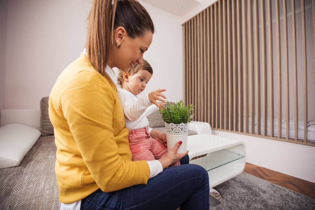 The picture is about a girl holding a baby and a plant which means to offer a service coupon for babysitting that gives friends or family a break when they need it most as your gift.