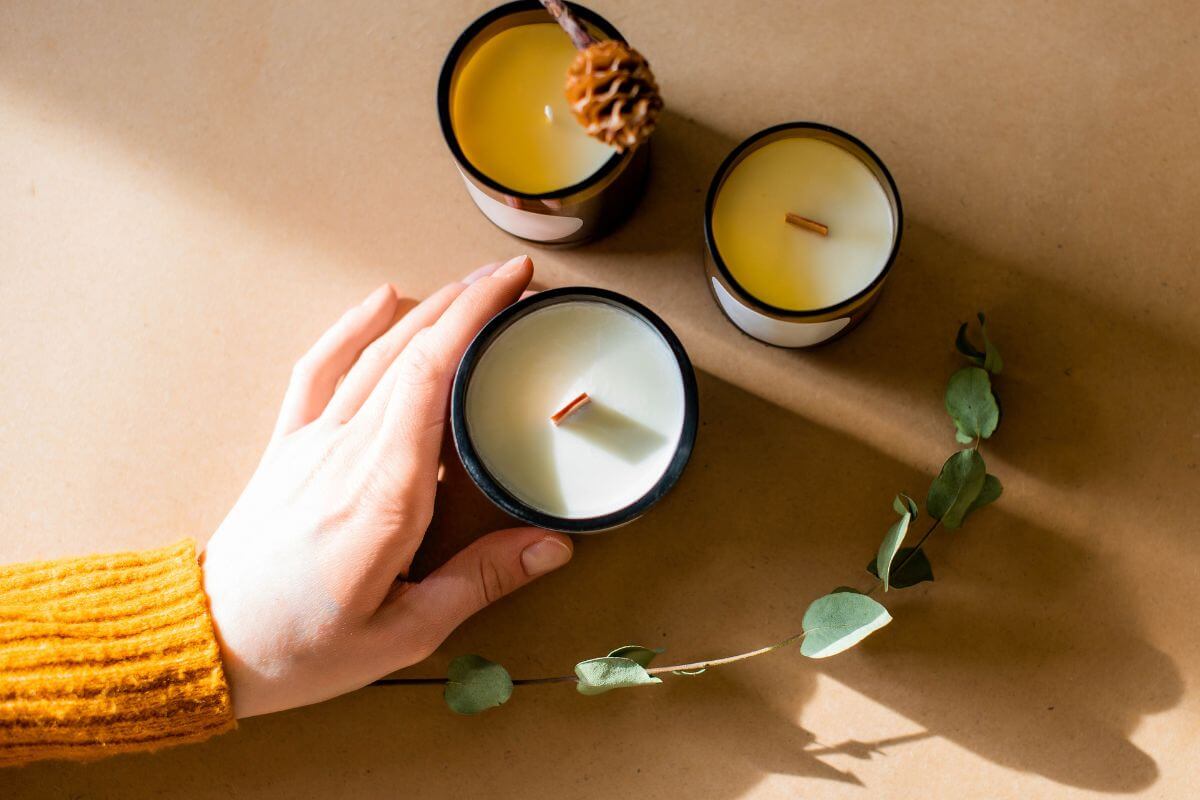 The image shows leaves, candles, and a girl's hand touching a candle, which means that handmade craft candles are thoughtful gifts that show creativity and care.