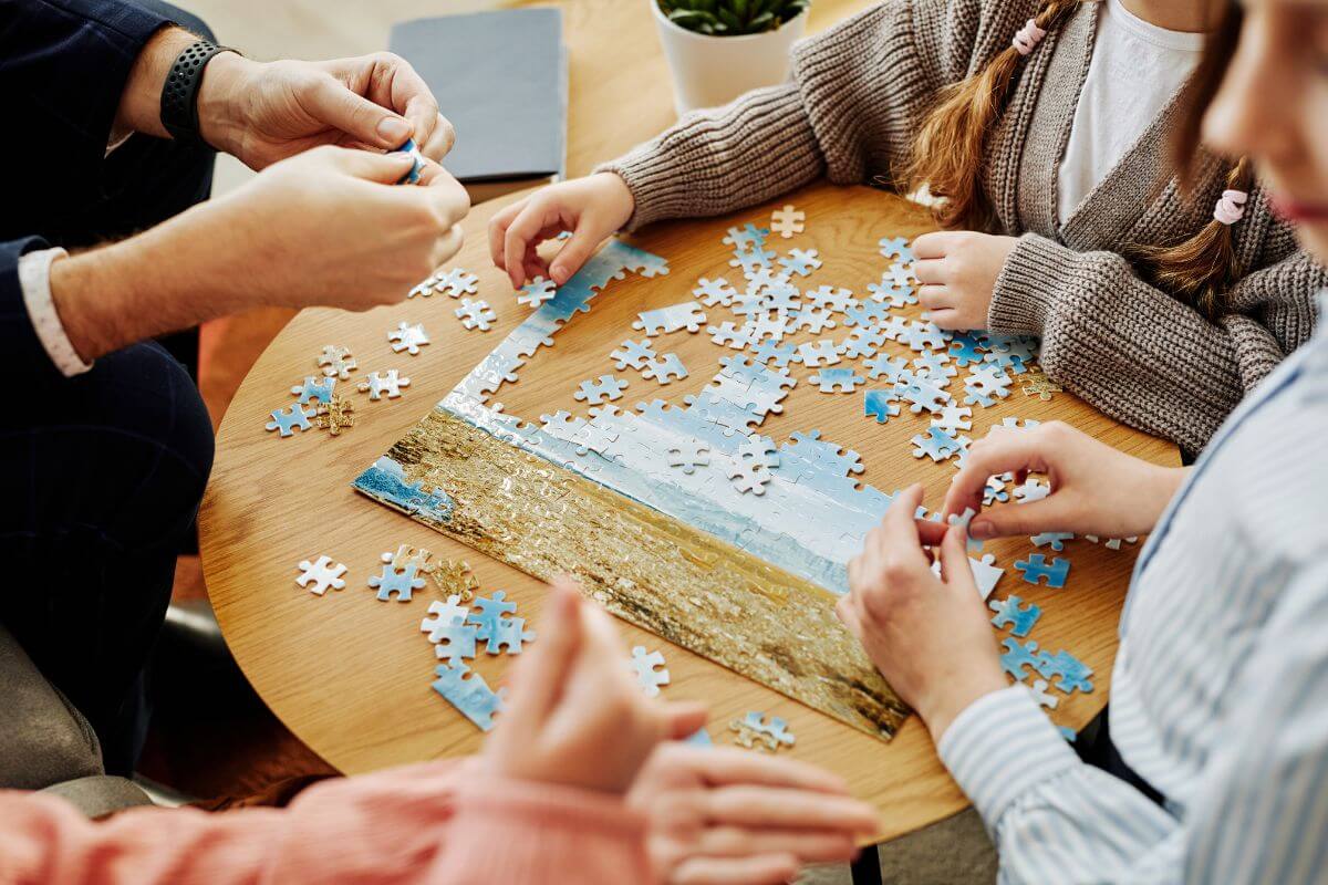 The photo tells about a group of people playing a puzzle game indicating to invite friends or family over for a relaxed night of games and quality together.