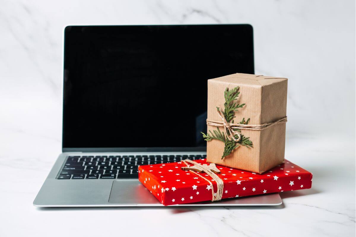 The picture tells about a laptop and gifts indicating to find more cheap Christmas gift ideas and enjoy a holiday season full of meaning not expense.