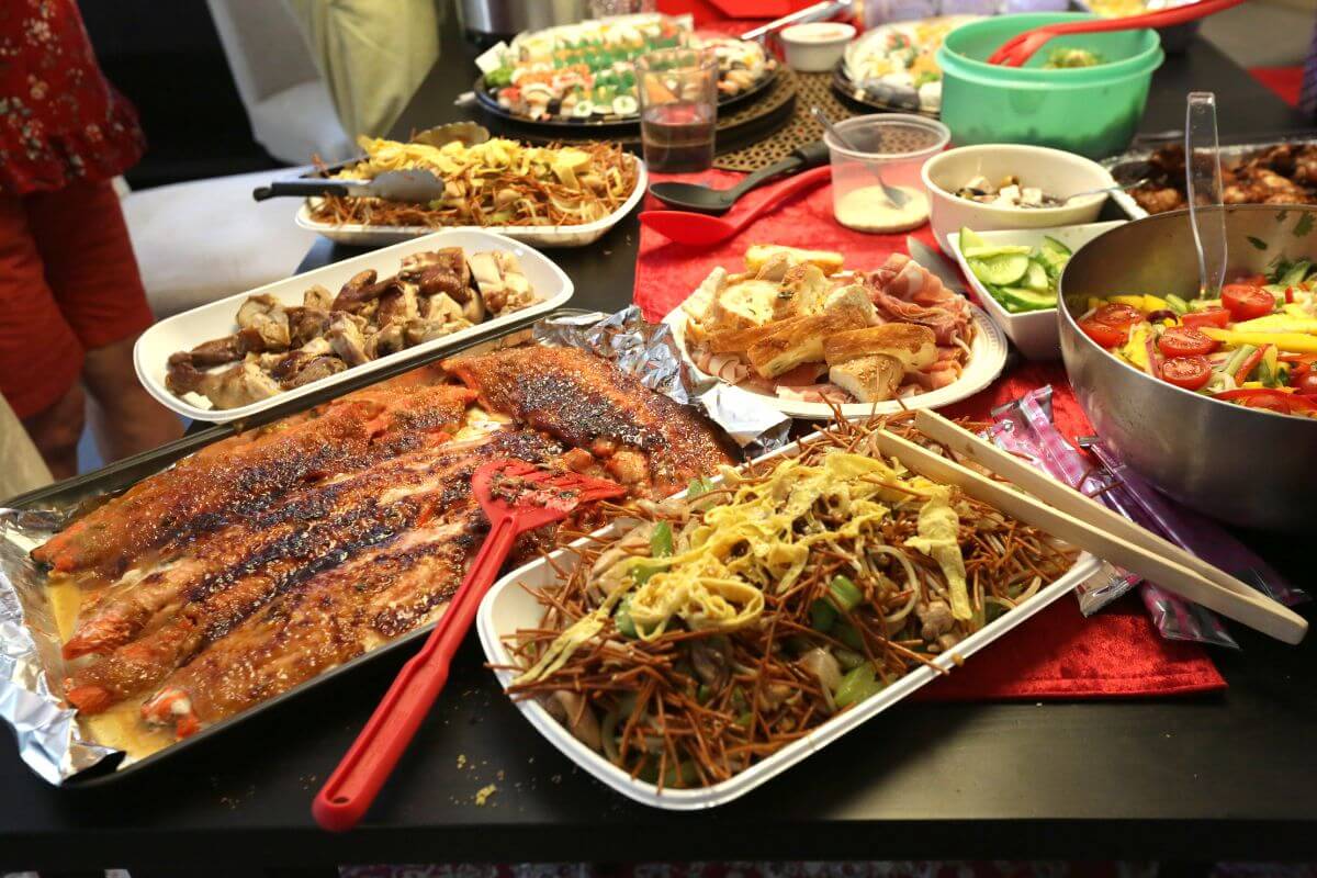 The photo shows food on the table with utensils which means hosting a potluck instead of covering all holiday meal costs and making the holiday meal more affordable.