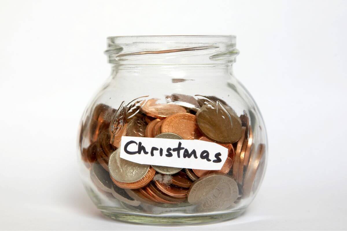 The picture of a jar filled with coins and with a note referring to starting saving for Christmas and avoiding debt when the holidays arrive.