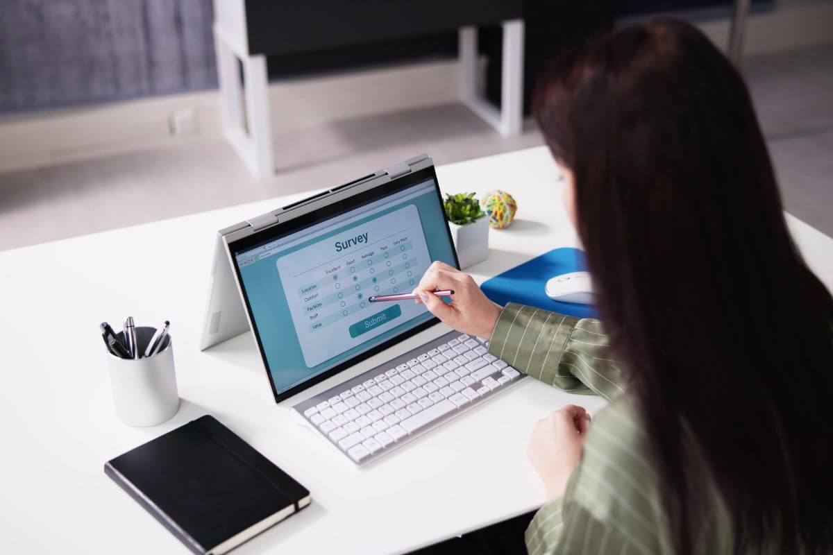The image shows a notebook, a pen, and a girl using a laptop which refers to participating in paid surveys as an easy way to make extra cash in your free time.