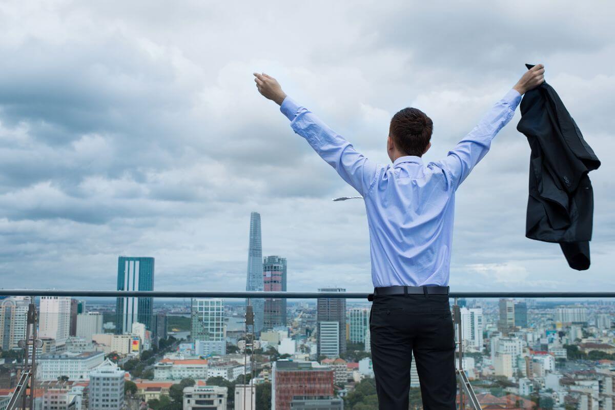 The image of the buildings and a man raising both hands refers to learning how to get more time with freedom in your life to reduce stress and focus on what truly matters.