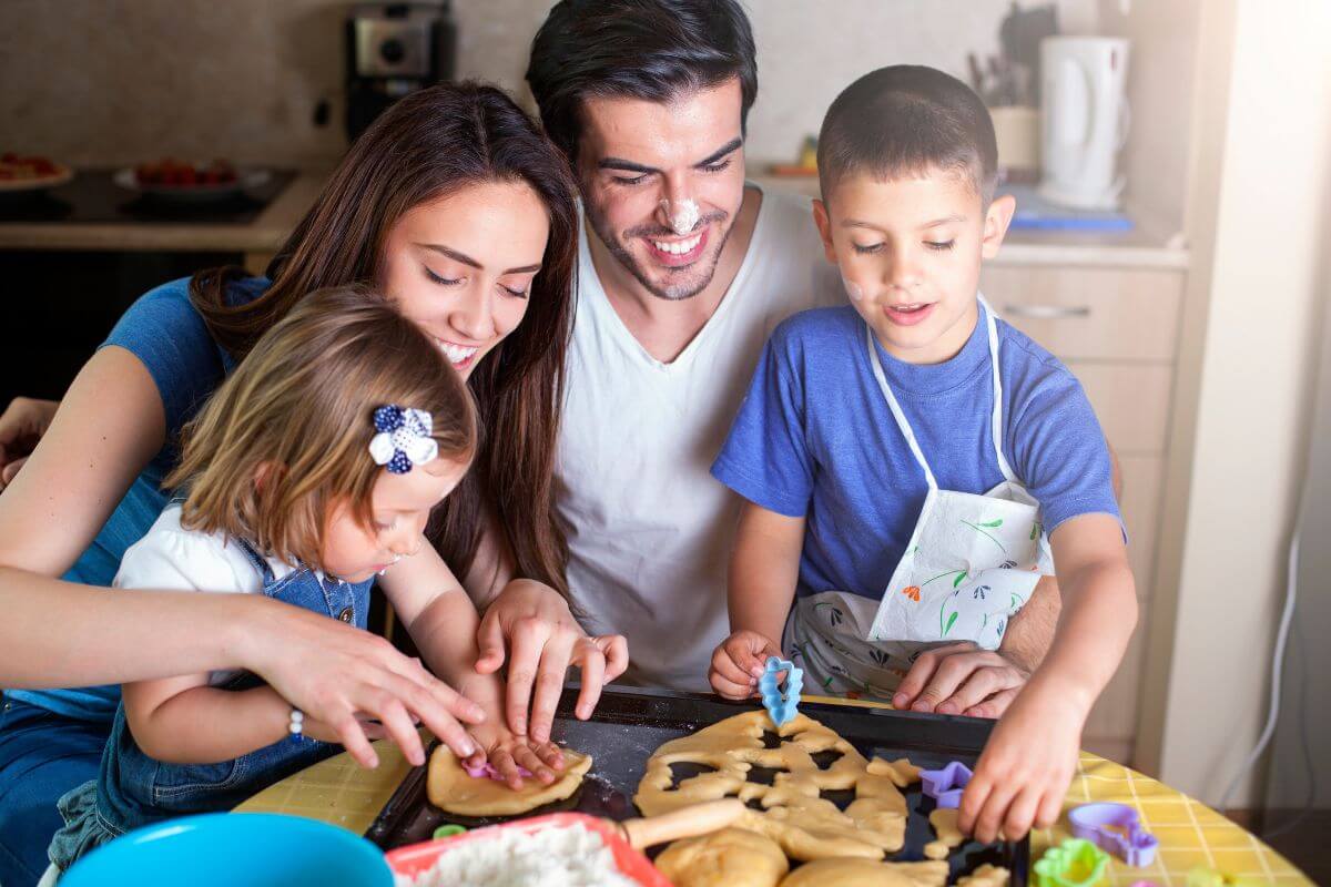 The image shows a group of family bake and decorating cookies together and enjoying the time creating something delicious. 
