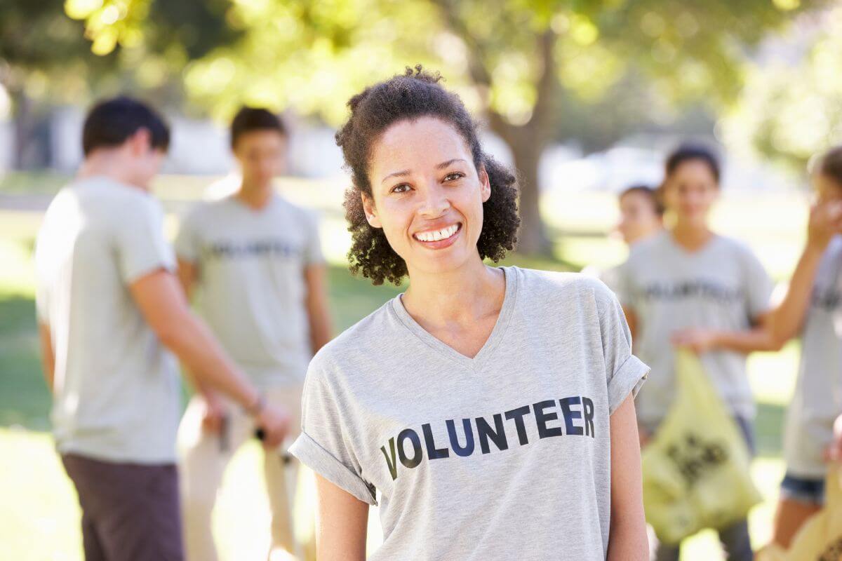 The image shows a girl together with her team at the back indicating to volunteer at a local shelter and makes the holiday meaningful for everyone.