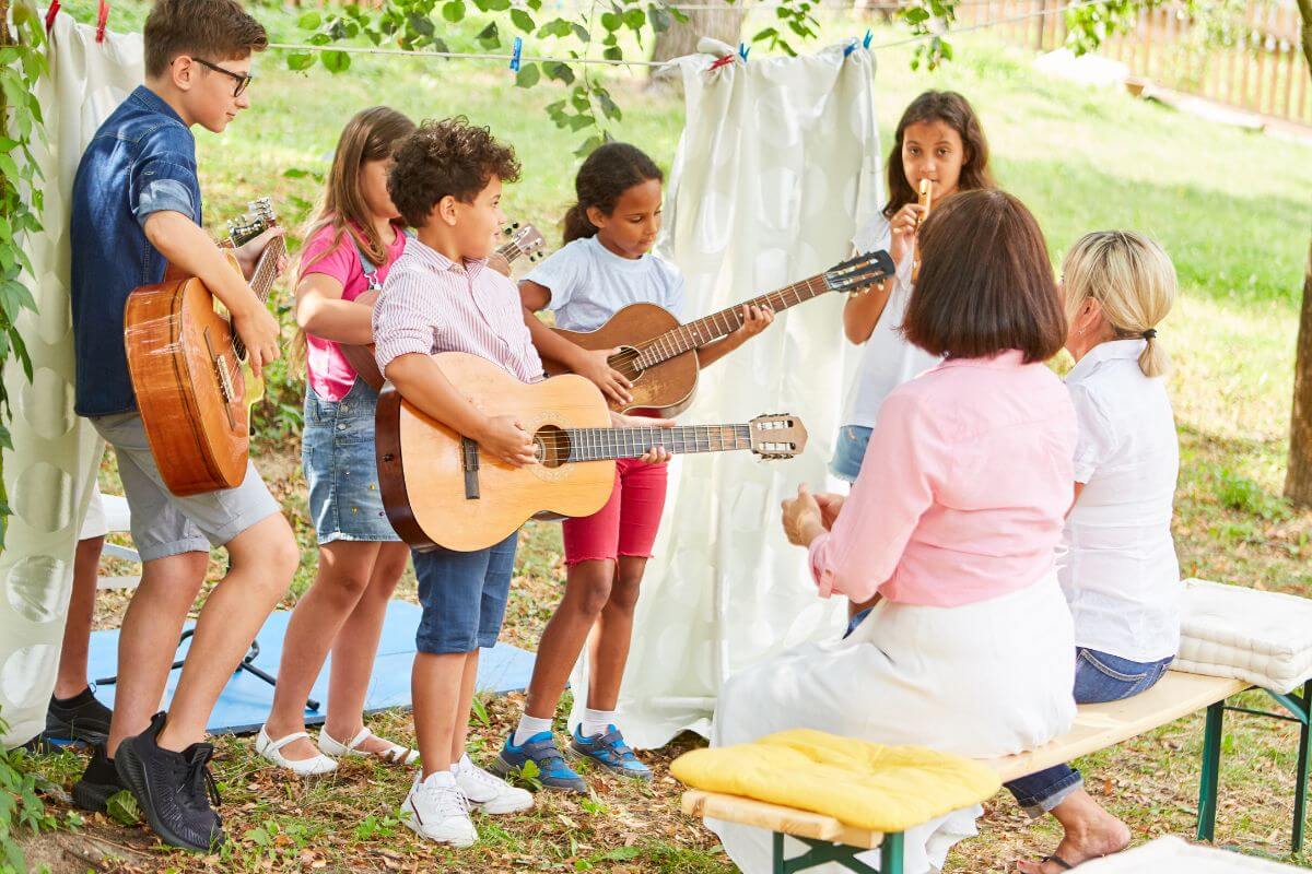 The picture tells about a group of children playing guitar together with their mom watching which means organizing a family talent show for a lighthearted holiday activity. 