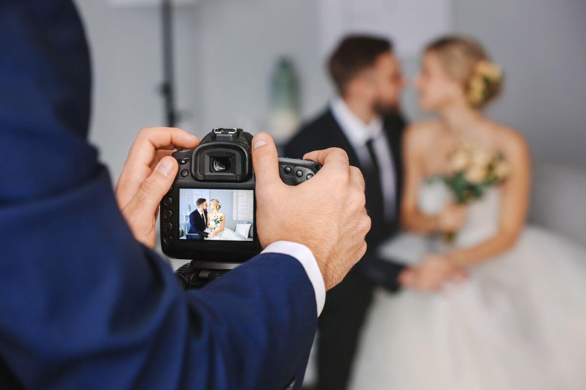 The photo shows a couple as a subject and a young man's hand holding a camera and taking a picture of the couple which means to offer photography services for events and turn it into a side hustle to earn while doing something you enjoy.
