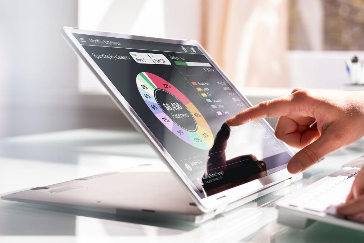 The picture of the girl's hand using a laptop with a screen display indicates to use of financial apps to help track spending and make it easier to stay organized. 