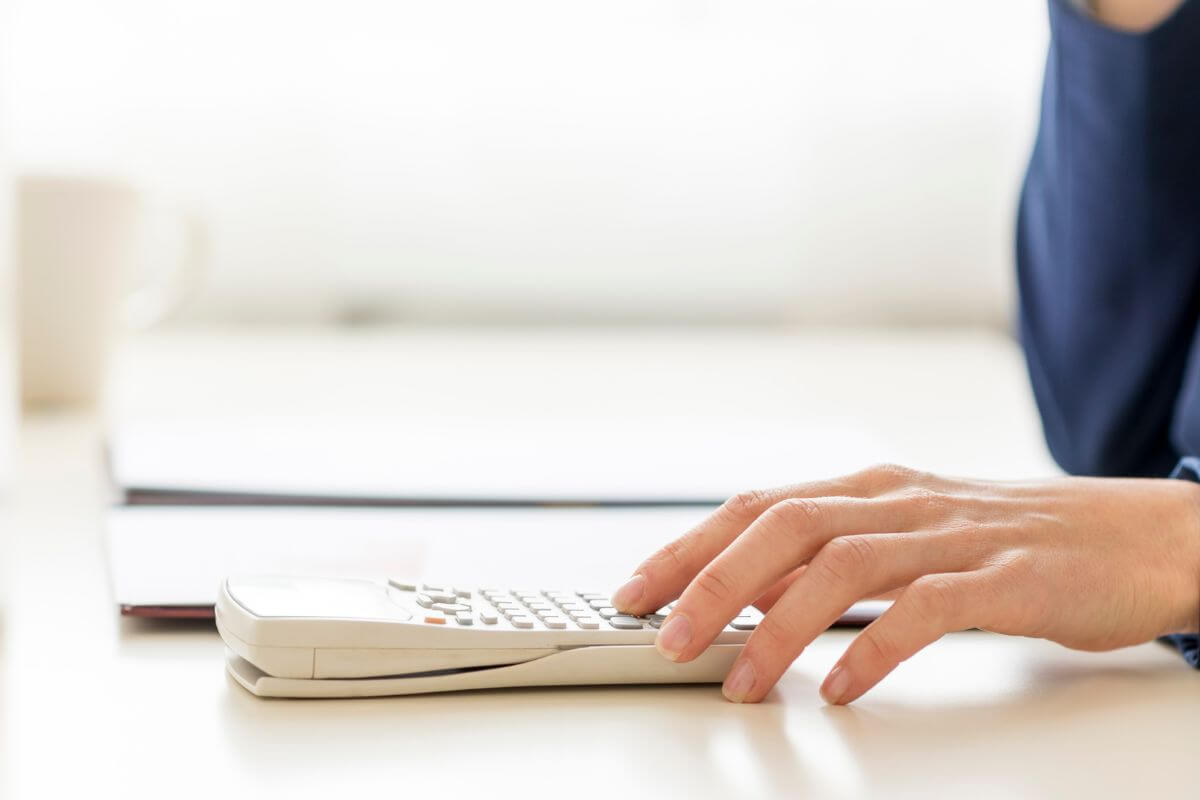 The image tells about the girl's hand using a calculator with the clipboard as reference which means debt-to-oncome ratio over 36% can signal financial strain.