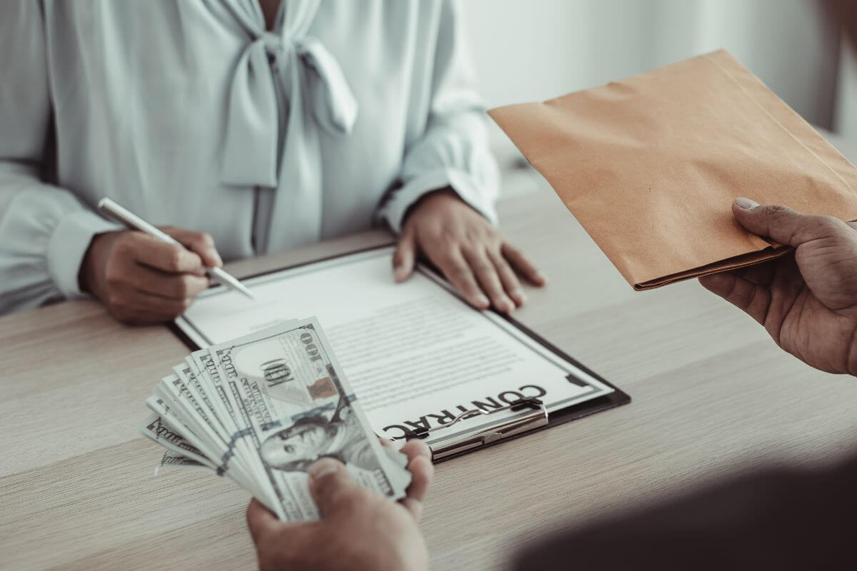 The picture tells about a debtor holding an envelope and dollar bills given to the client who signed a contract which means taking on new debt to pay old debt can lead to a dangerous cycle. 