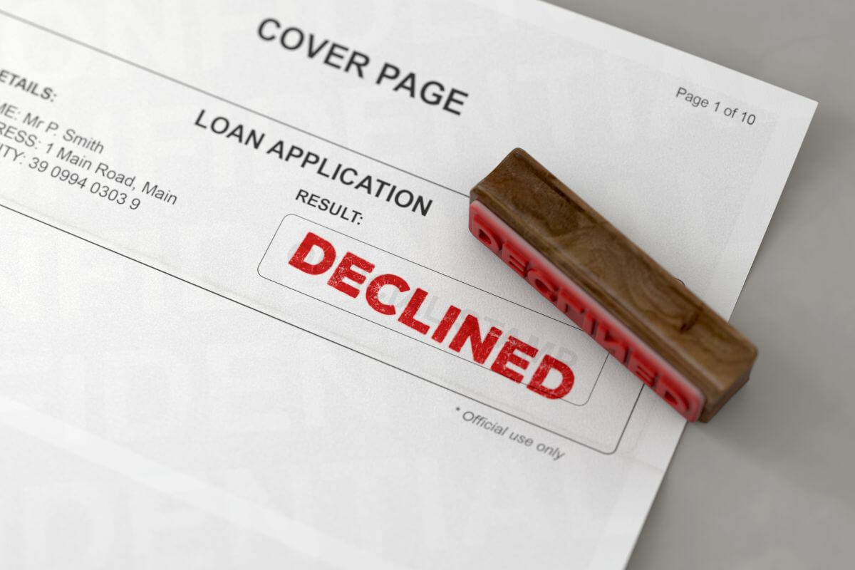 The picture tells about the wooden stamp and a piece of paper with notes and red embossed notes referring to the unable to qualify for loans due to high debt also can hurt your chances of getting approved for new credit.