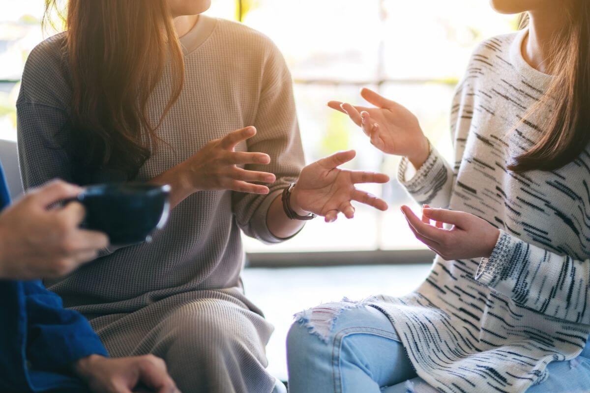 The picture shows a group of people talking together indicating to talk openly with trusted friends or family and sharing your struggles with someone you trust can give you support and new ideas.
