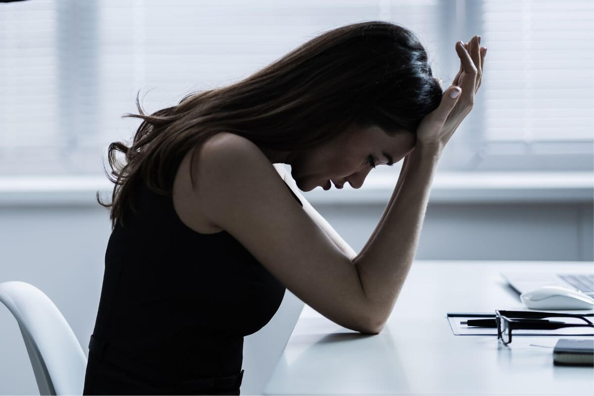 The image shows a girl bent down and putting her hands on her forehead indicating that avoiding blaming yourself won't help you instead of using those as lessons to make better choices and move forward.