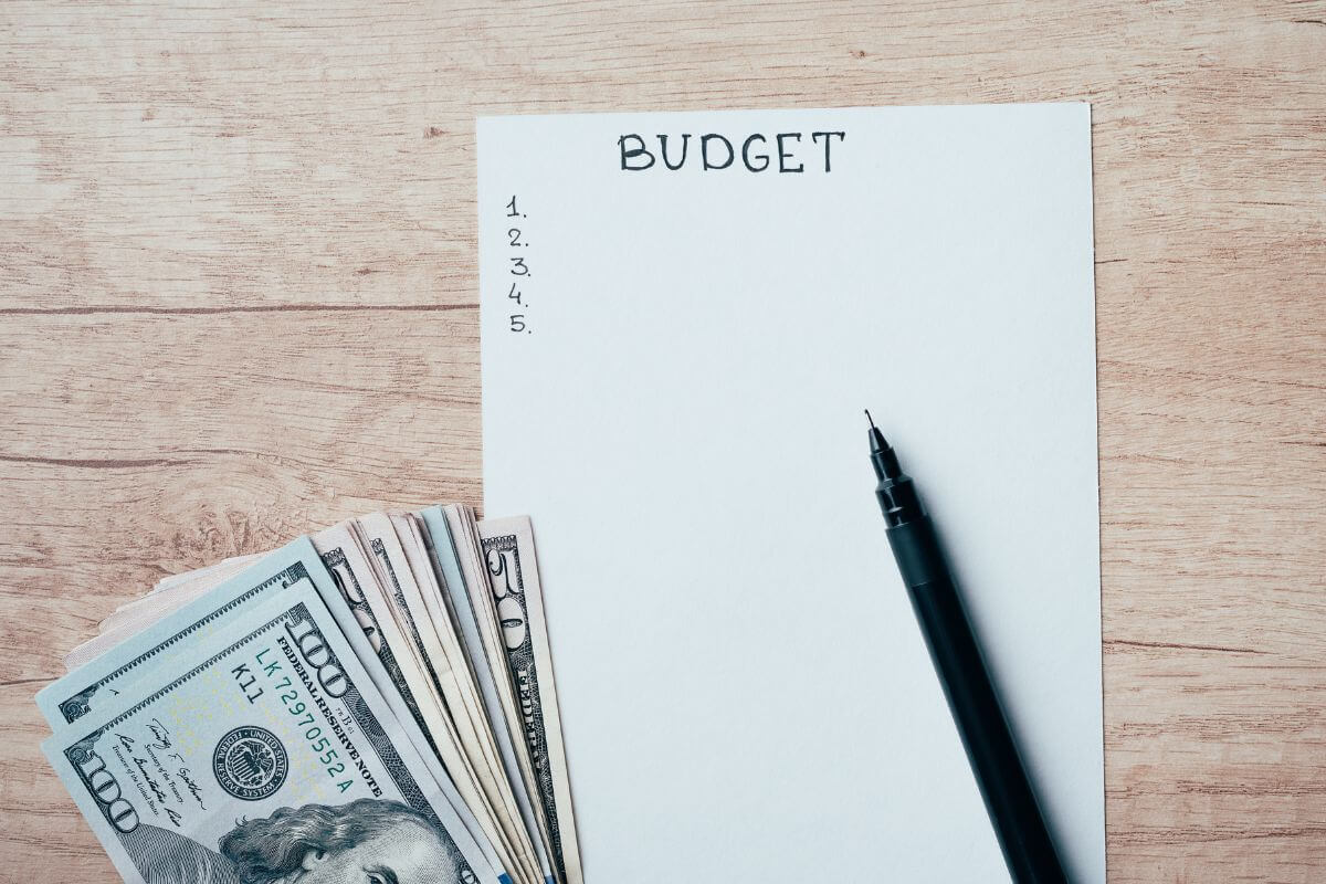 The photo tells about dollar bills, a pen, and a piece of paper with notes referring to the focus on building financial habits that can build the financial future you want over time.