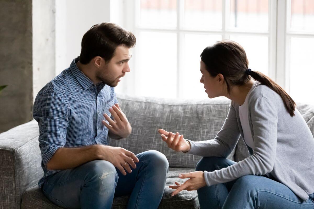 The picture tells about a couple pointing at each other indicating to avoid blaming or criticizing each other's spending habits can lead to defensiveness and fights.