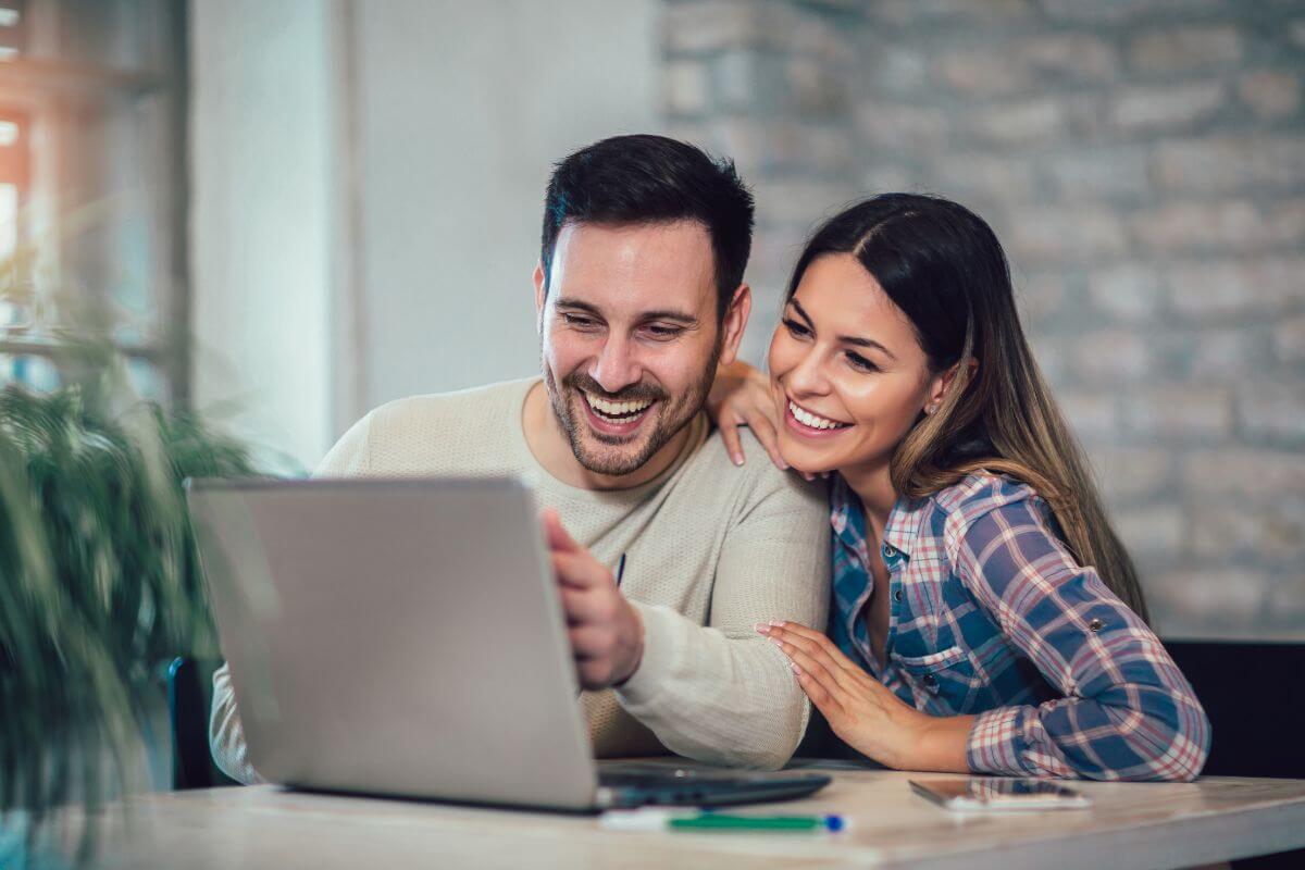 The picture tells about a couple using a laptop together which means using financial tools to track progress together to make money management less stressful.