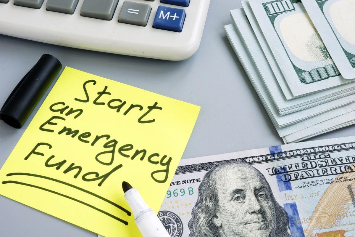 The picture tells about dollar bills, a marker, a calculator, and a piece of yellow paper with notes which means to set up an emergency fund for unexpected emergencies to avoid adding to debt.