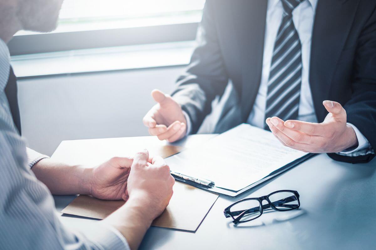The photo tells about an eyeglass, a clipboard, a client, and a creditor which refers to negotiating lower interest rates with creditors and helping you pay off debt faster.