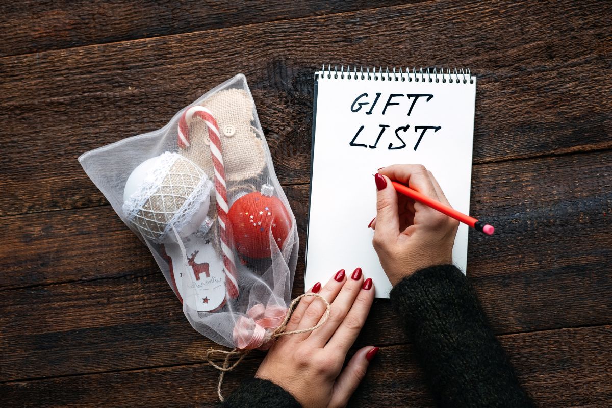 A woman's hand writing a gift list.