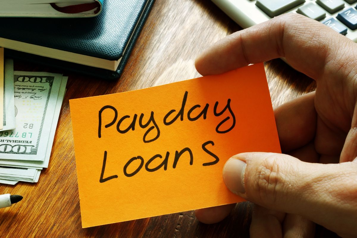 A man's hand holding a paper with payday loan wording.