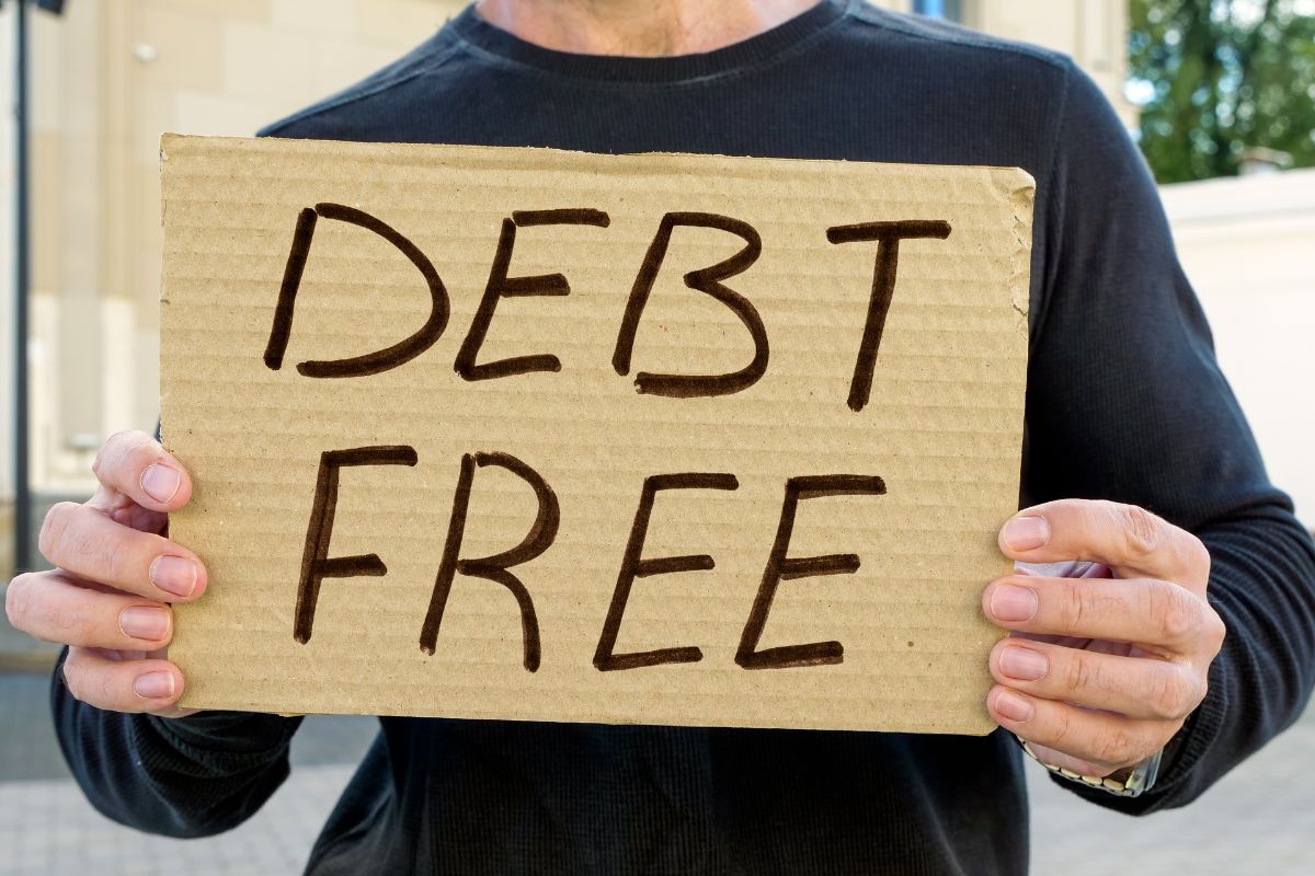 A man's hand holding a debt-free poster.
