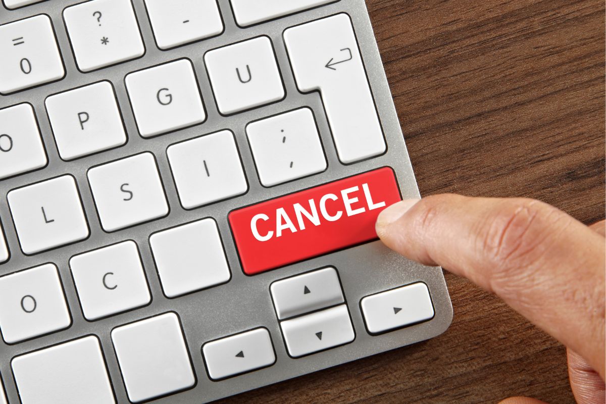A man's hand tapping a cancel button.
