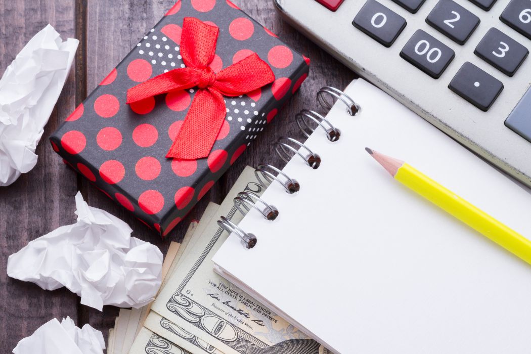 Photo of a gift, money, a calculator, and a notebook.