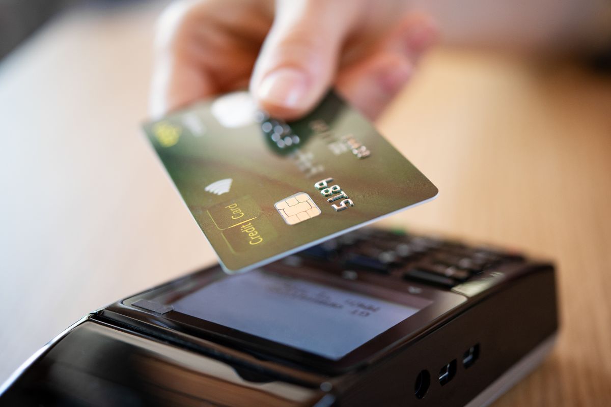 The image shows a woman's hand paying with a credit card.