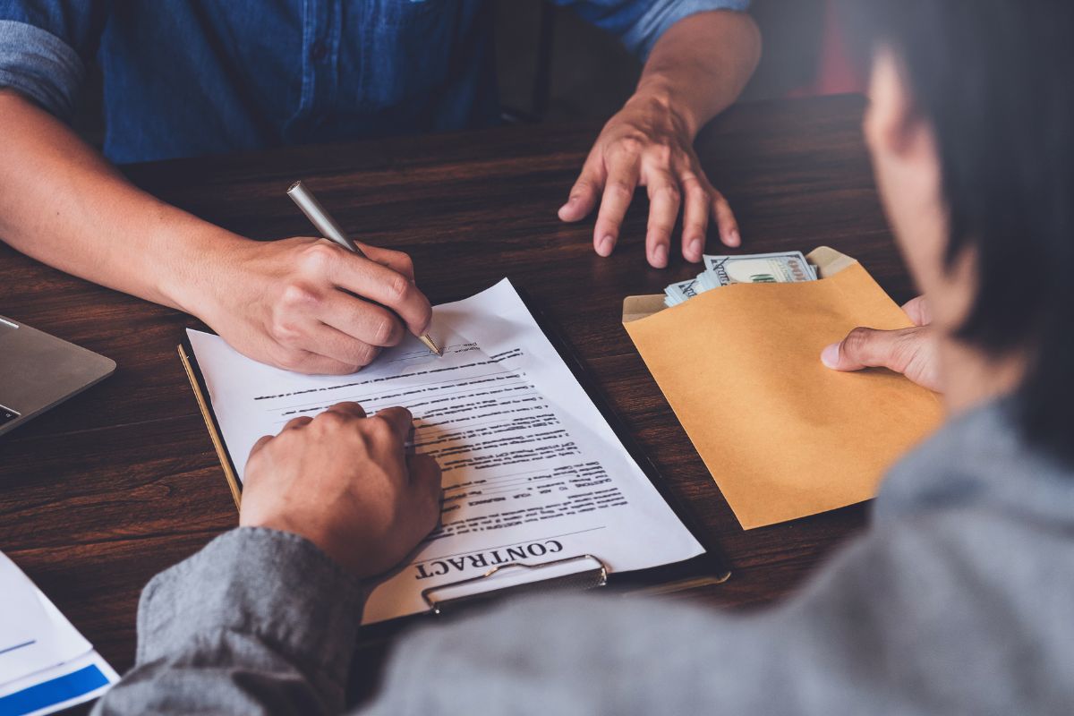 The photo shows a man signing a loan contract.