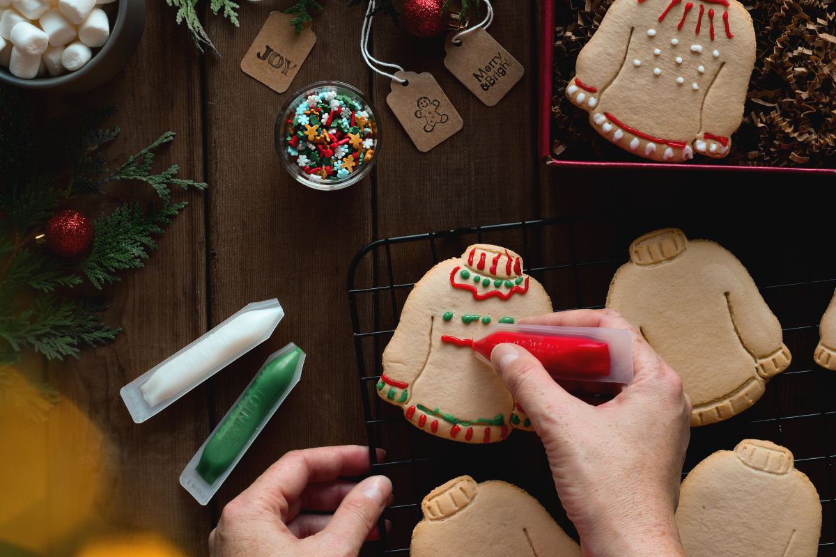 A woman's hand decorating holiday cookies.
