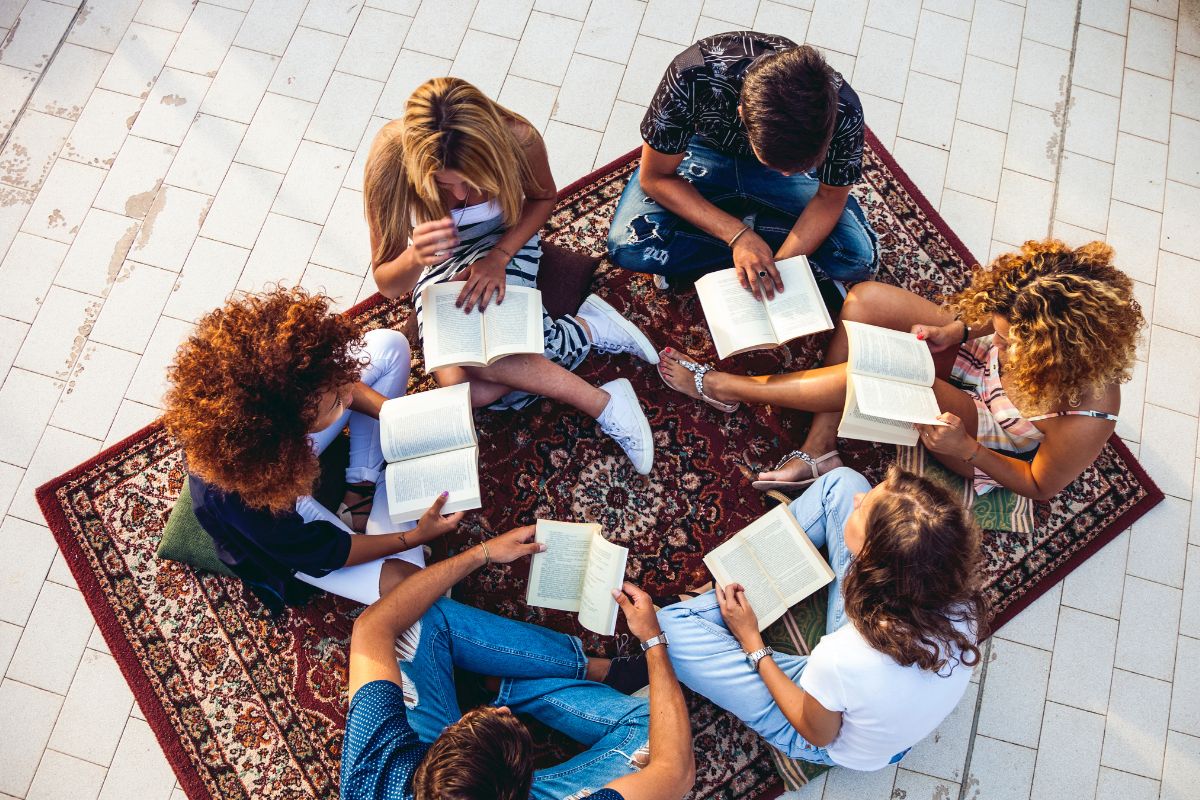 The image shows a group of friends reading books.