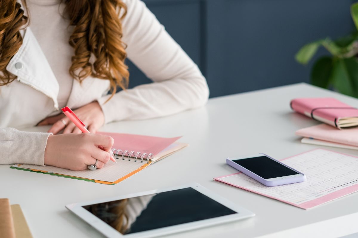 Photo of a woman writing on a notebook.