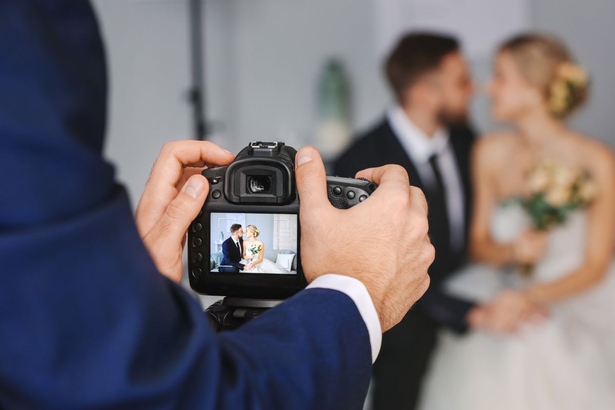 A young man taking a picture of a newlywed.