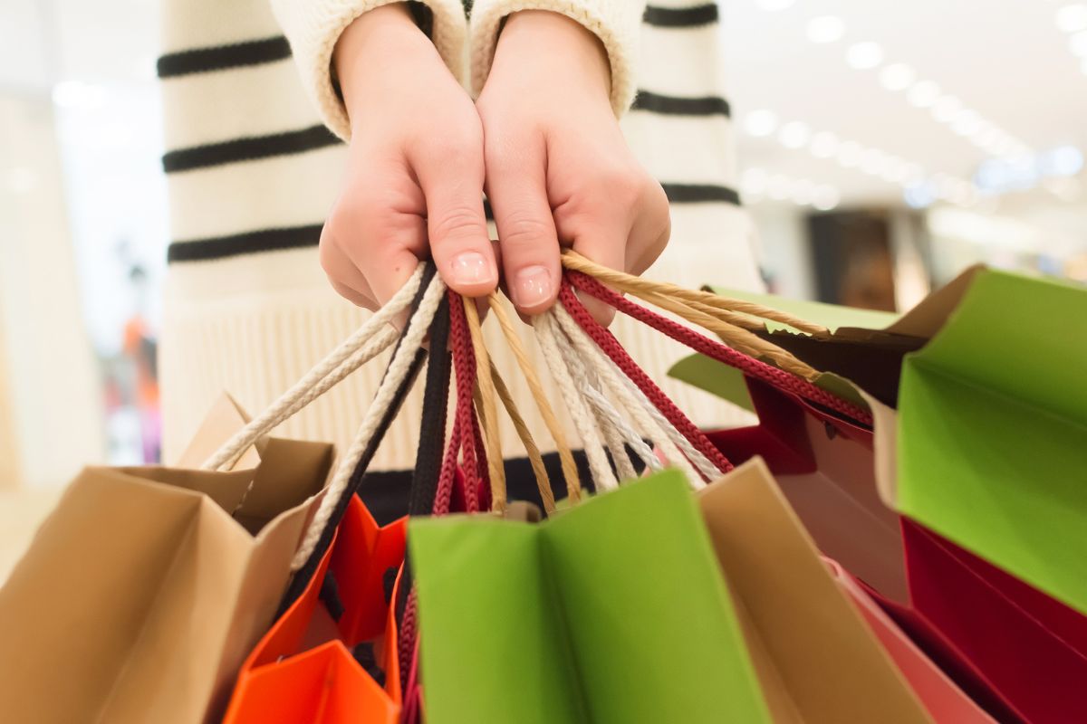 A mão de uma mulher carregando sacolas de compras.