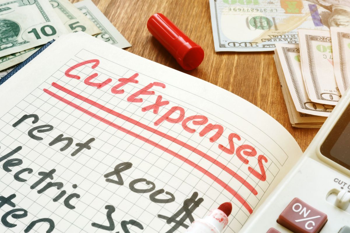 Image of a notebook with cut expenses wording.