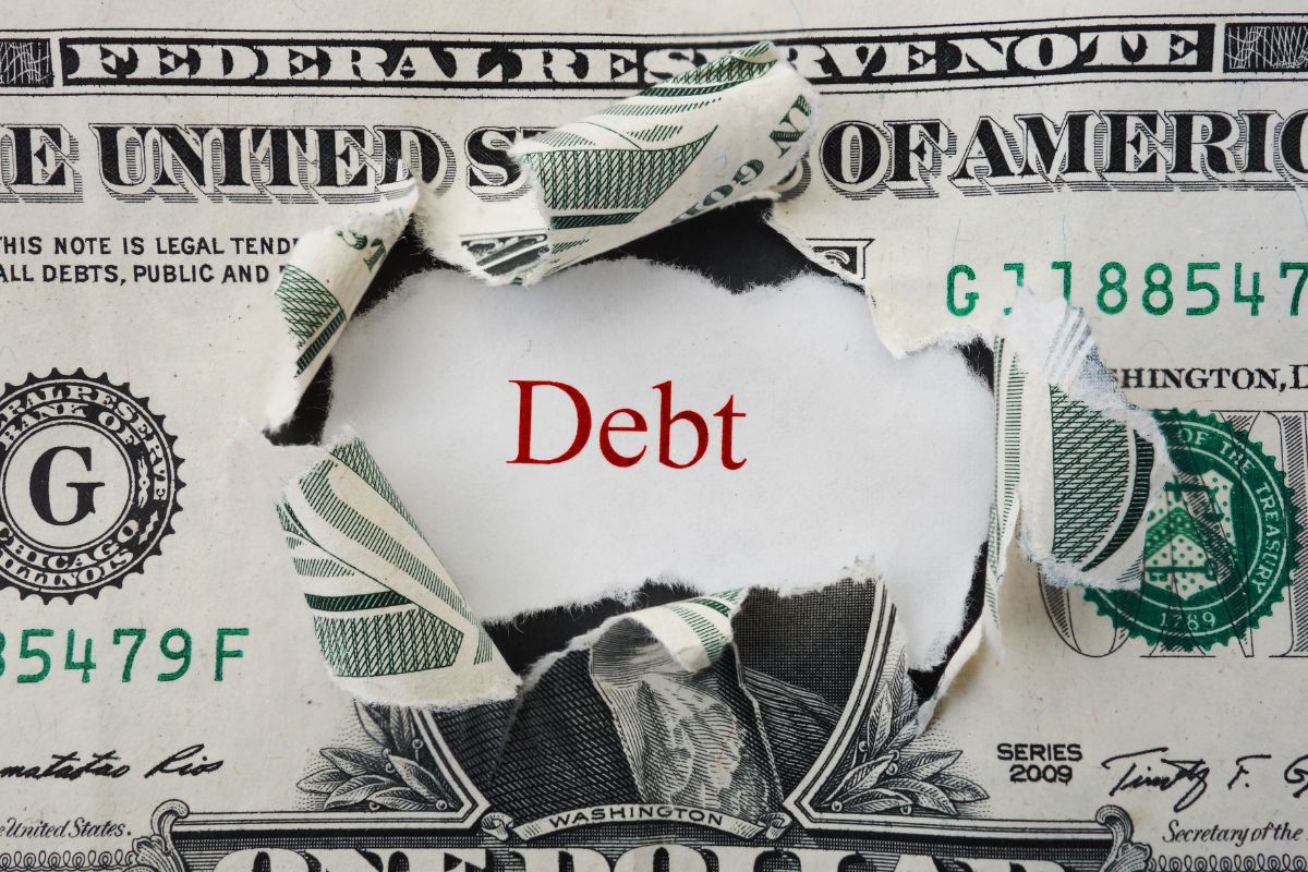 Picture of torn money and debt wording.
