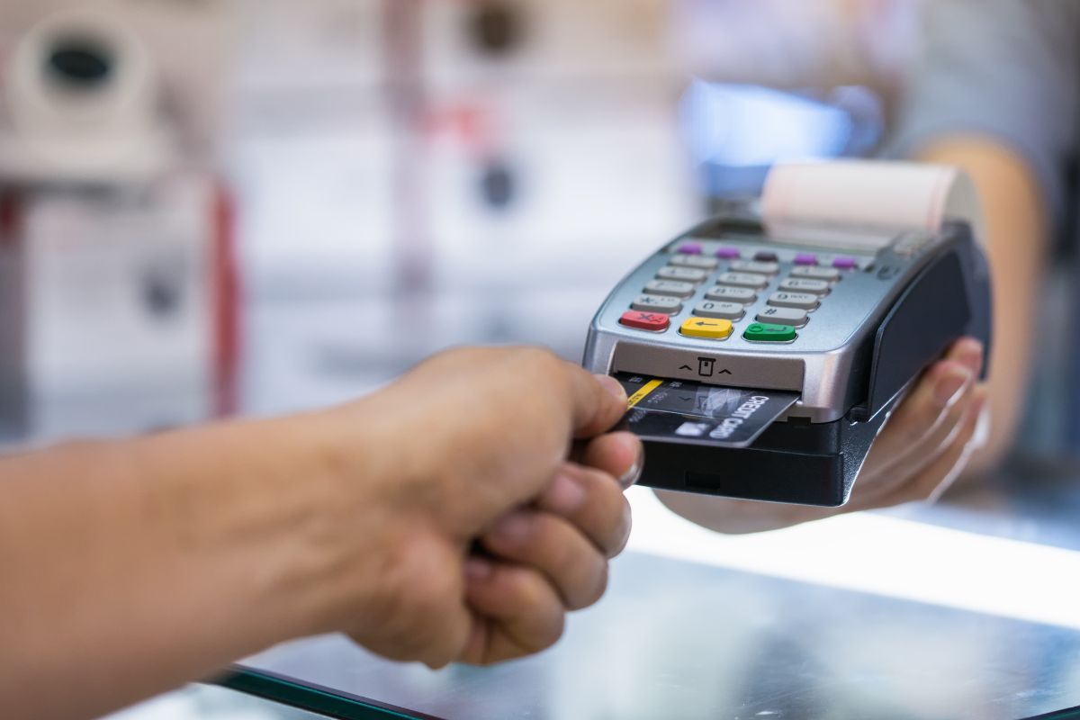 A man's hand paying with a credit card.