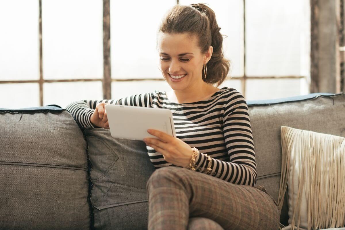 The picture tells about a girl sitting on the couch while using a tablet device which means to cancel unused subscriptions and memberships and redirect that money toward savings or debt repayment.