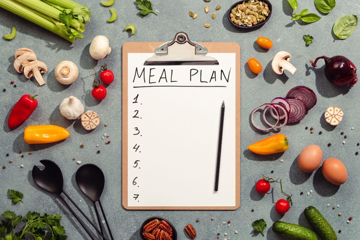 The photo tells about vegetables, eggs, a spoon, and folk, and a clipboard with paper and pen with notes referring to planning meals around sales and discounts keeps grocery bills low and avoids food waste by buying only what you need.