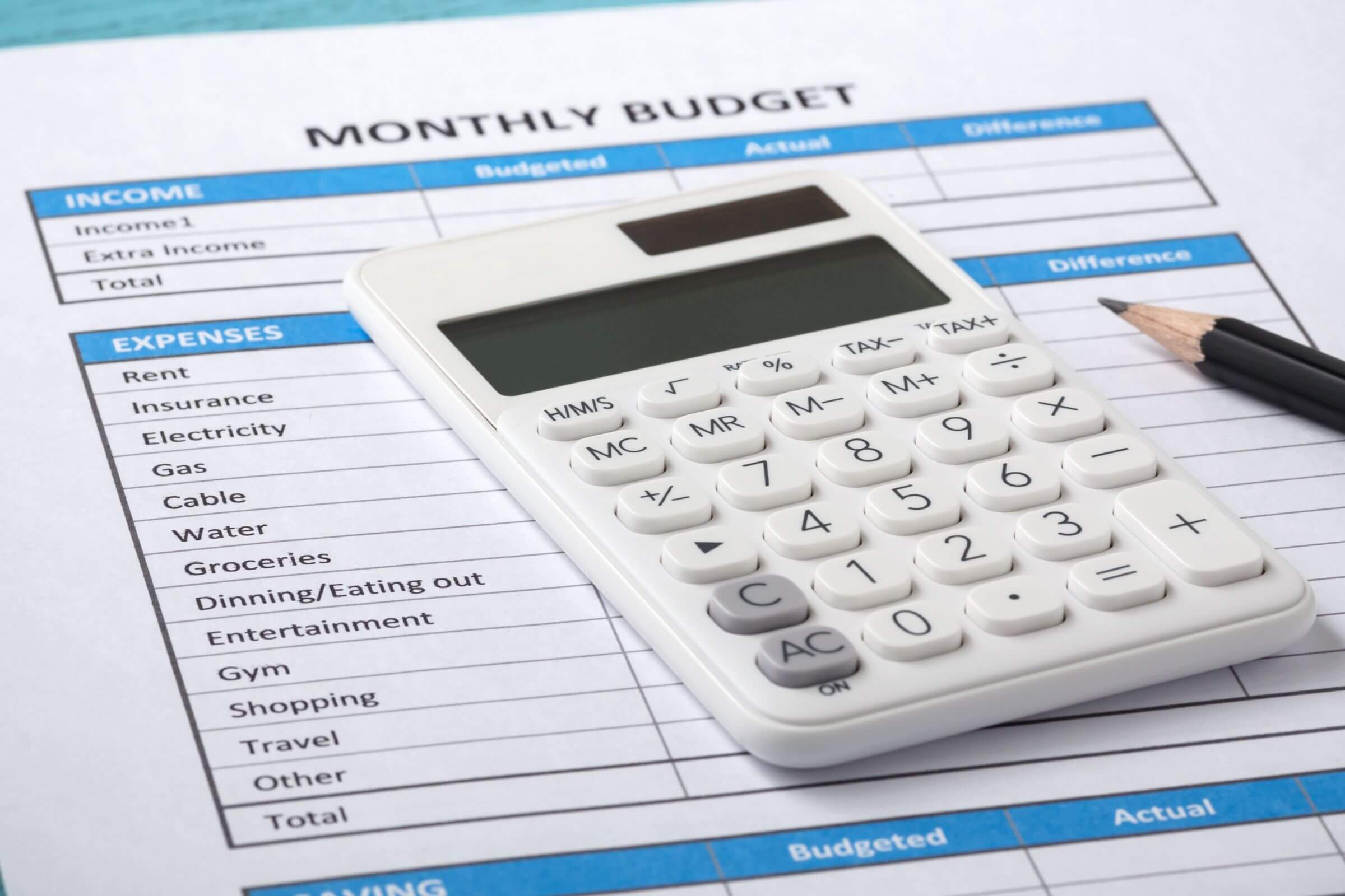 The image tells about a pen, a calculator, and a piece of paper with notes referring to creating a monthly budget and sticking to it that helps you see where your money goes and keeps you in control.