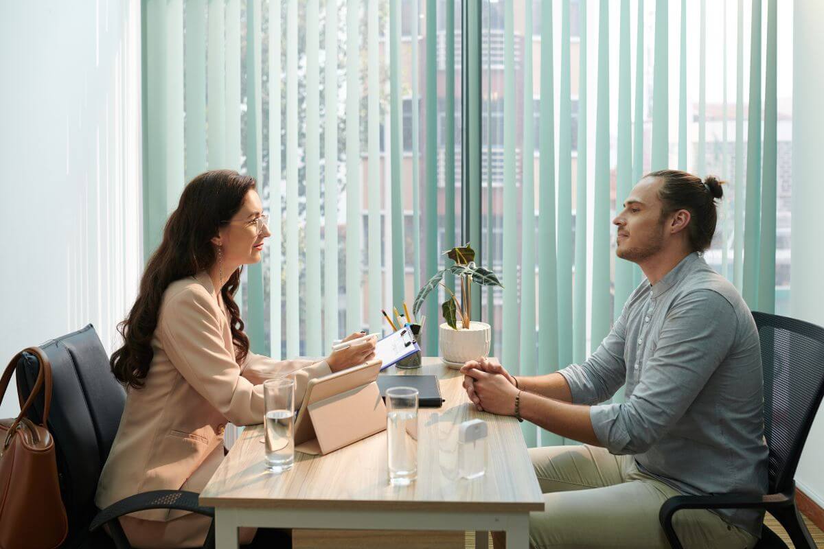 The photo tells about a plant on the table, glasses of water, a tablet, and two people talking together which refers to planning and negotiating for a salary increase that can make a big difference in reaching your financial goals faster.