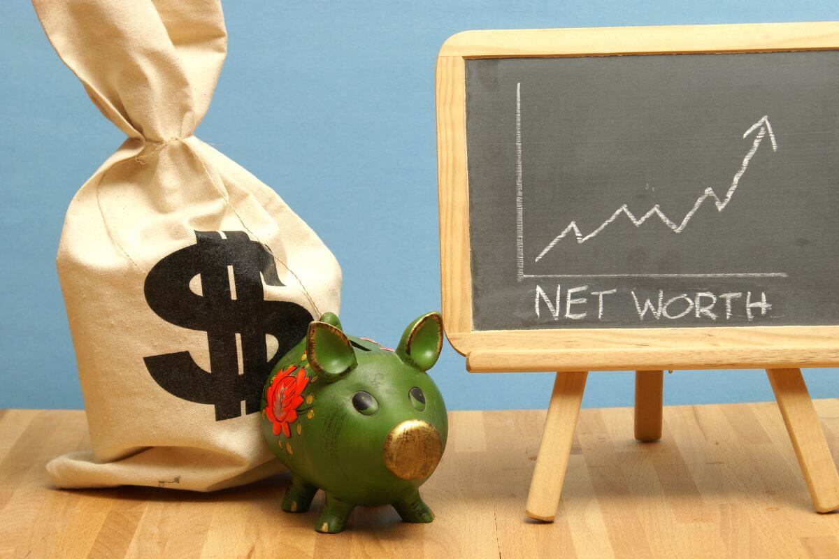 The picture tells about a money bag, a piggy bank, and a blackboard with notes and a graph which refers to tracking your net worth monthly or quarterly to measure success and stay motivated to reach financial independence. 