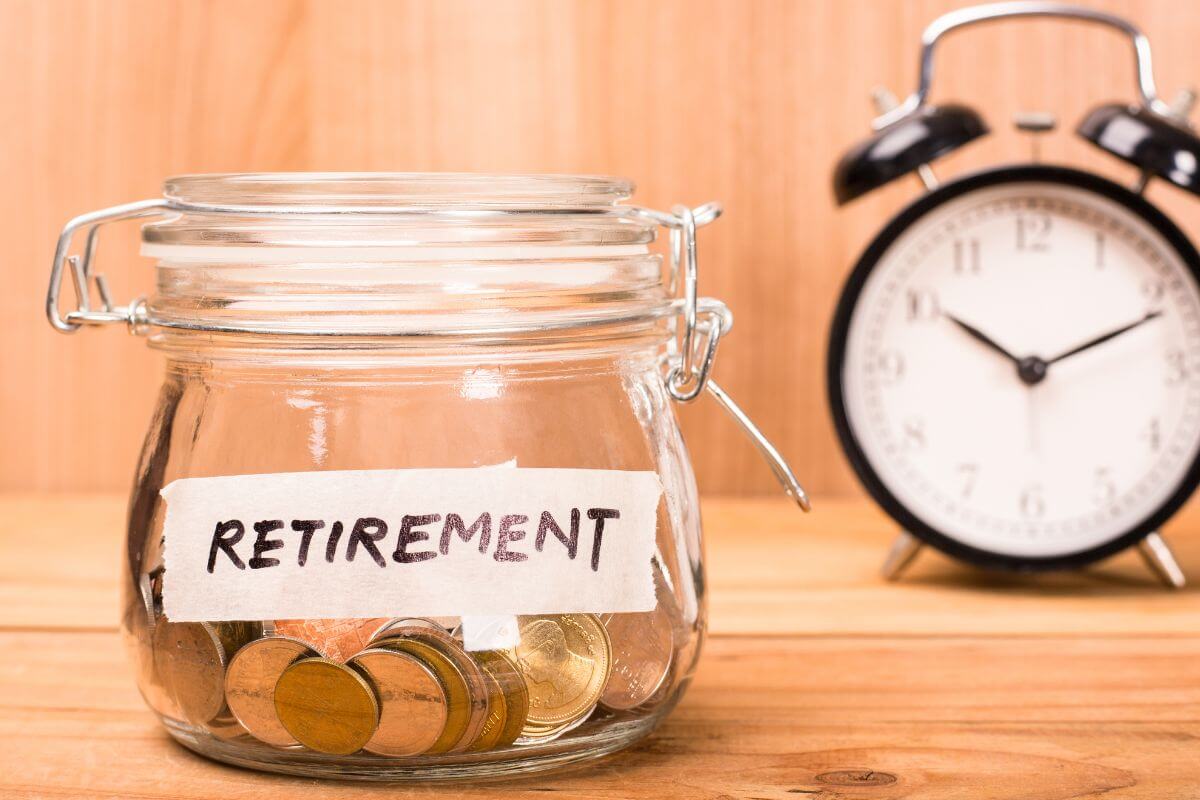 The image of a clock and a jar filled with coins and with a note indicating to increase contributions to retirement that lowers your taxes today and grows your money instead of worrying about finances.