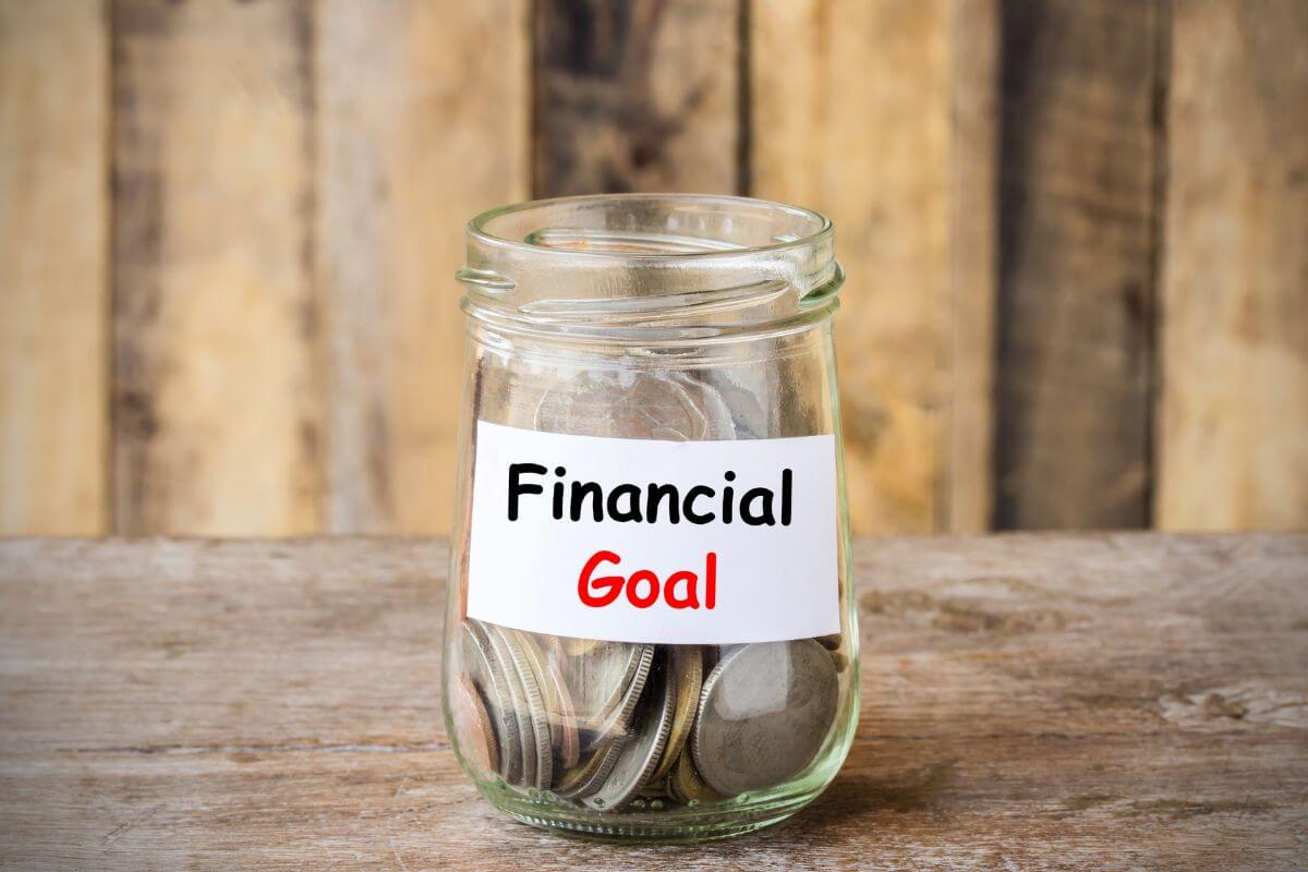 The photo of a jar filled with coins and notes referring to setting clear short-term and long-term financial goals gives you direction for your money that keeps you focused and motivated.