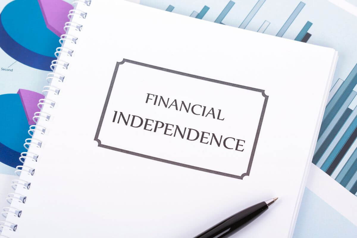 The photo tells about papers with graphs and a notebook with notes referring to a plan for achieving financial independence gives you direction and purpose.