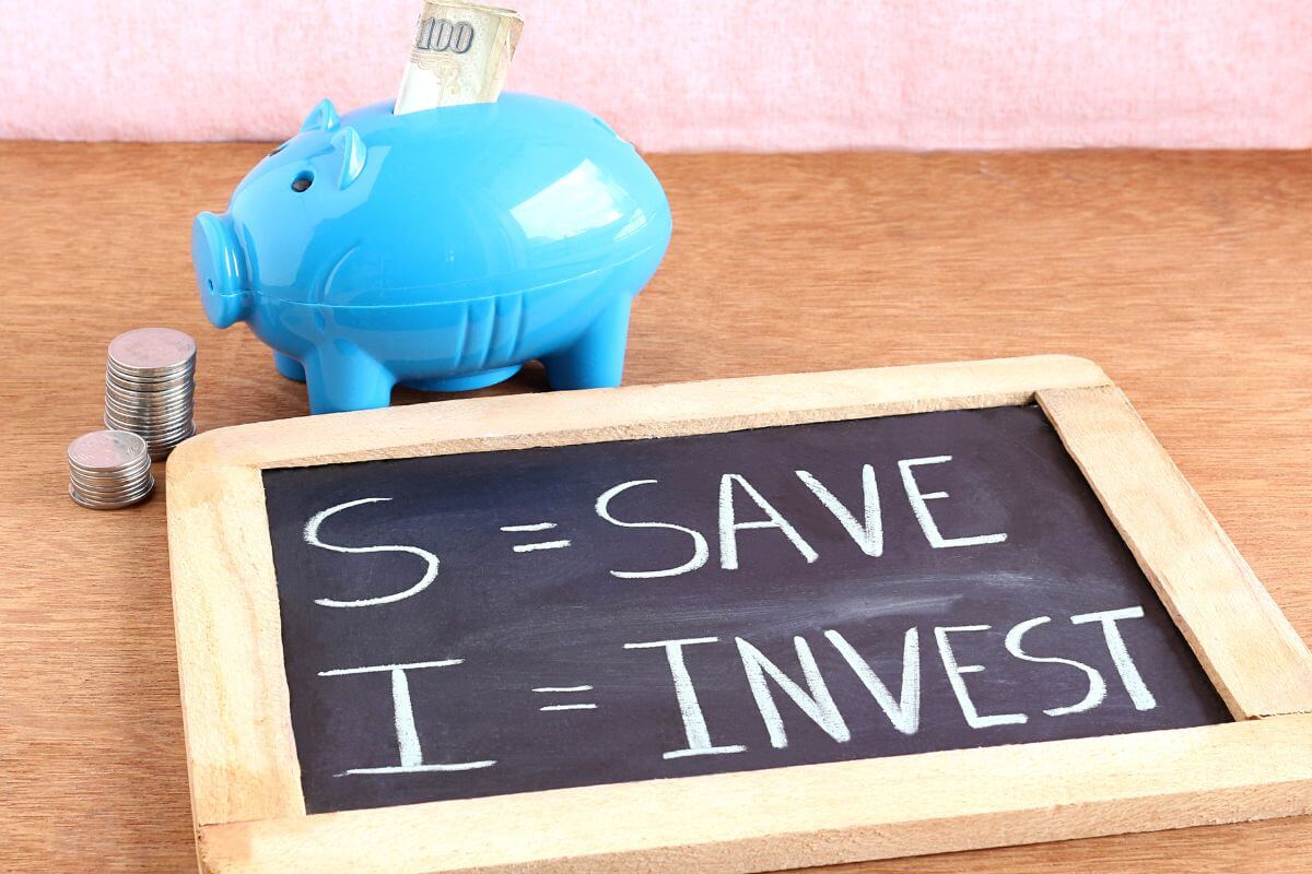 The image shows coin stocks, a piggy bank, and a blackboard with notes indicating to able to save or invest in your income helps grow your net worth and builds a solid financial foundation.