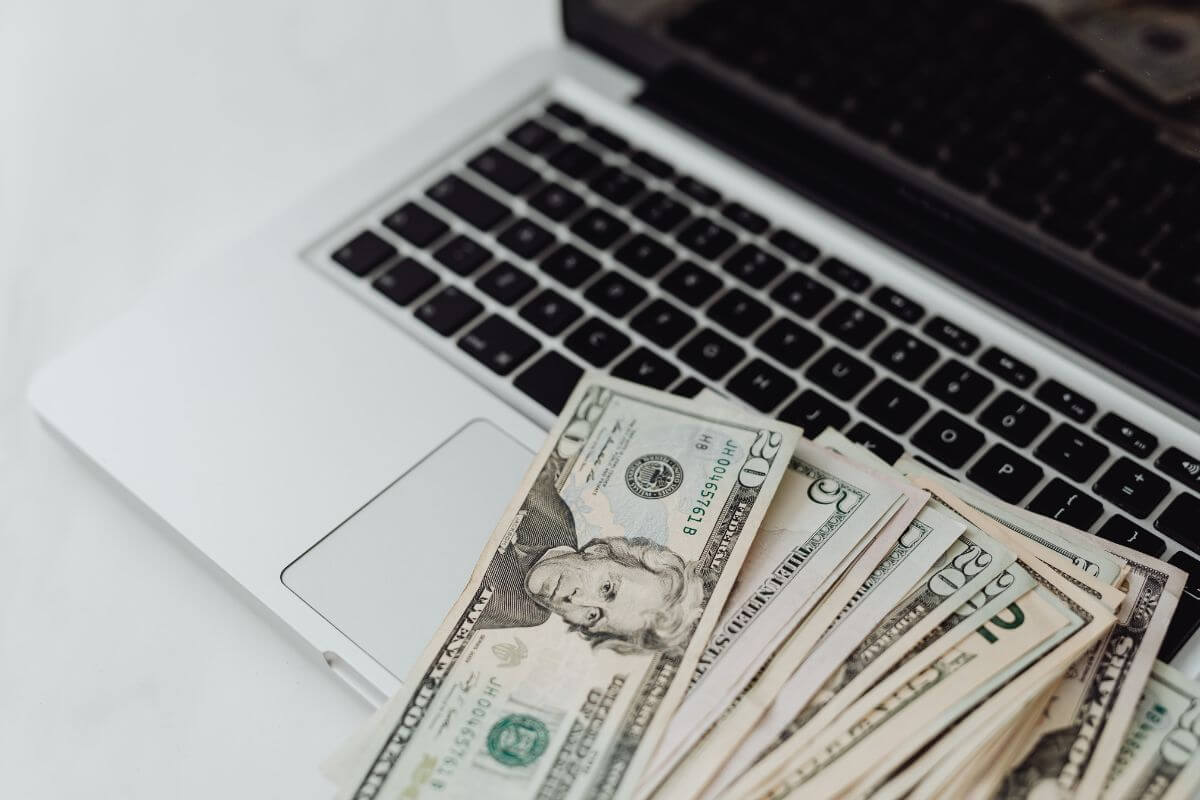 The image shows a laptop and dollar bills indicating to automate everything so you stay on track without constant effort.